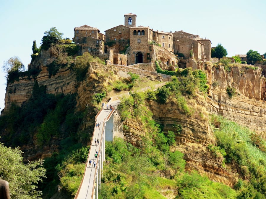 Civita di Bagnoregio Italy, view from the top, people walking on the bridge leading to the town, town on the rocky mountain