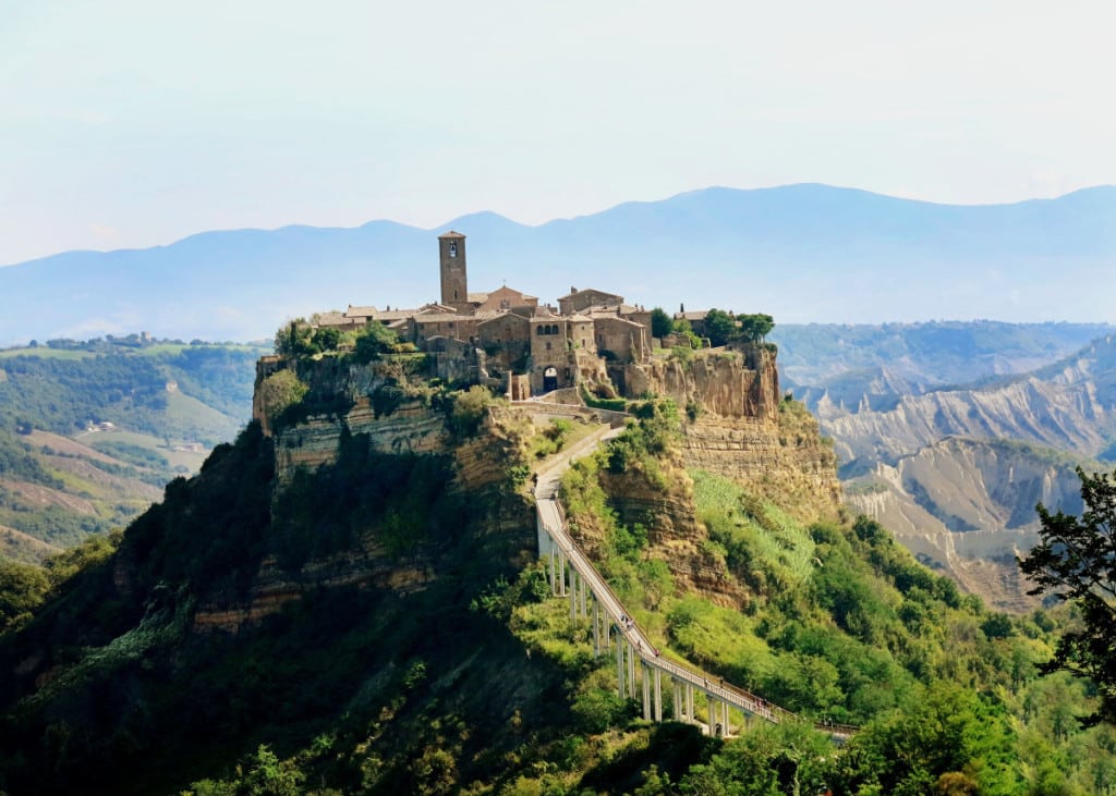 Civita di Bagnoregio Italy, the dead city on the top of the mountain, stone buildings, tower, bridge leading to the town, mountains all around