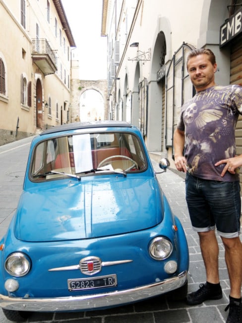 Assisi, Italy, man in the street standing next to a very small blue car