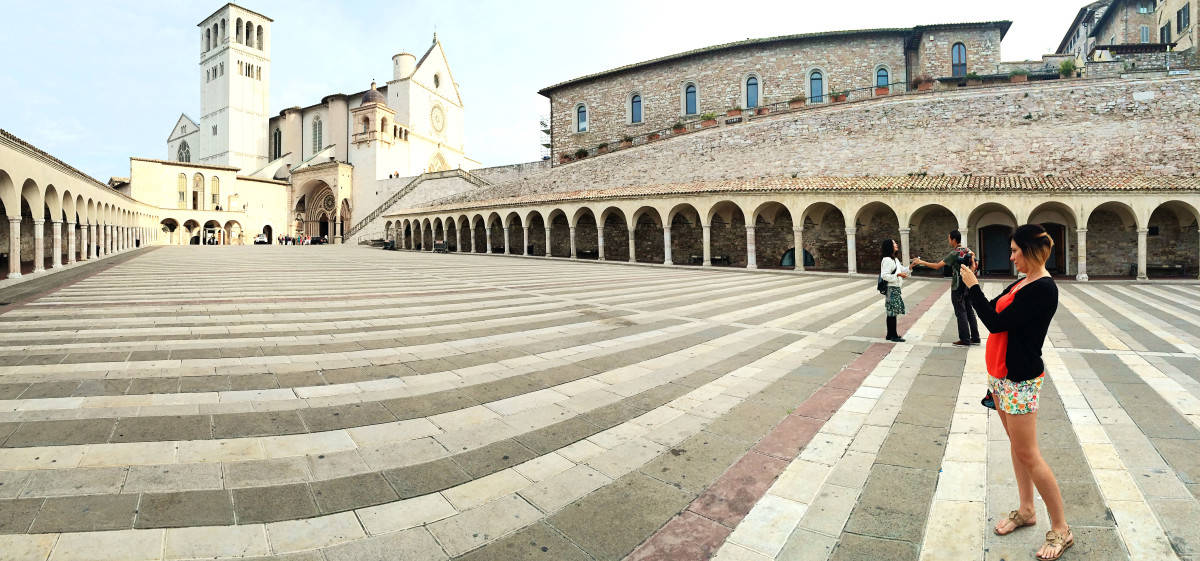woman taking an photo in the stripy square of the cathedral in Assisi, Italy, 