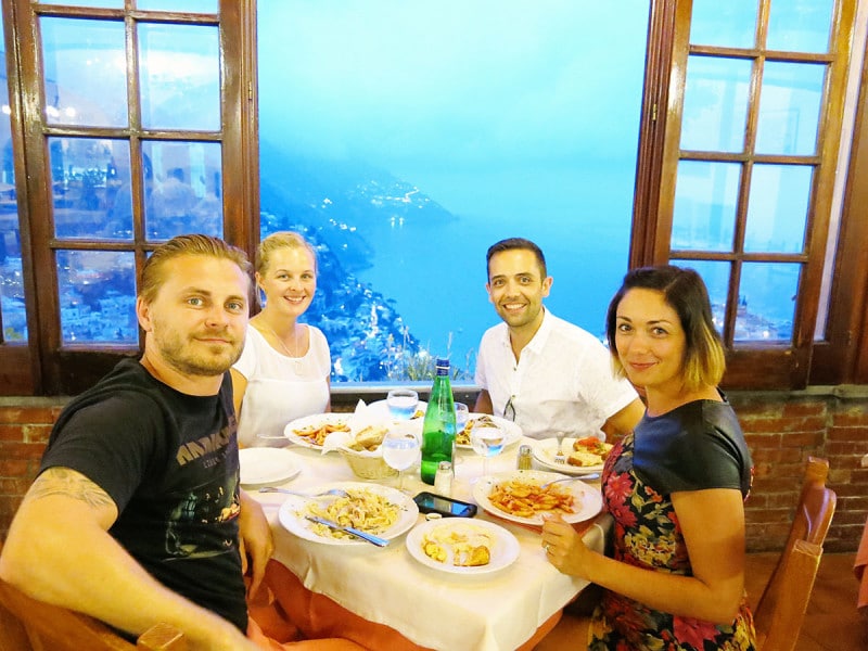 Dinner setting Italian restaurant in Positano, Amalfi Coast, two couples, view over the town of Positano in the evening