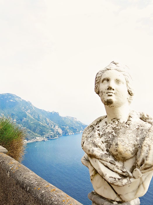 Ravello, Amalfi Coast, Italy, white and grey old statue on the side of the concrete barrier, coastline in the background
