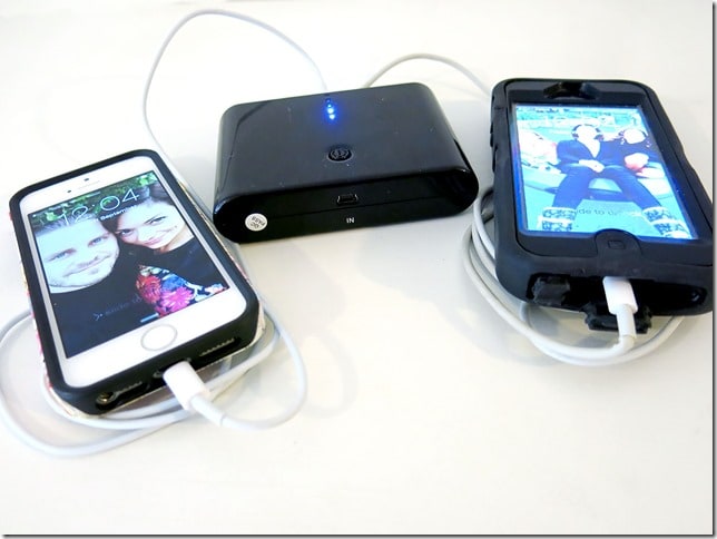 Portable phone charger connected by cables to two iPhones