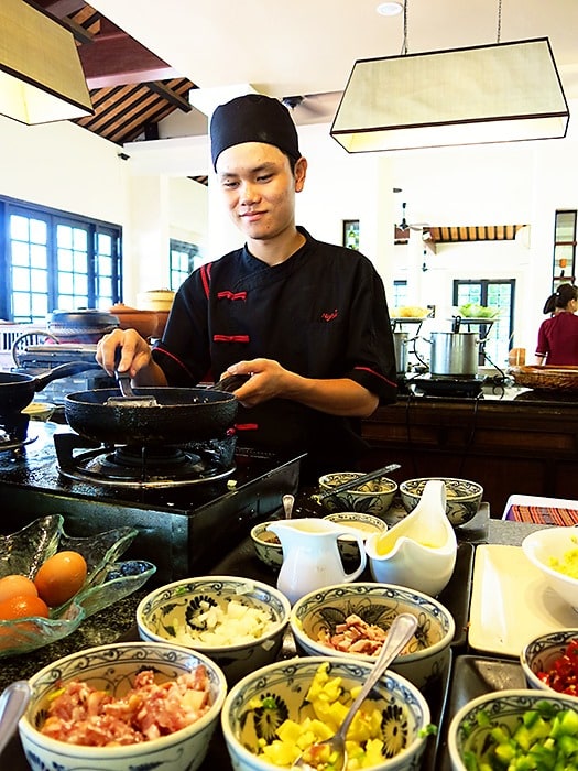 Victoria Hoi An, Vietman, a cook preparing food in the restaurant, frying, condaments on the table