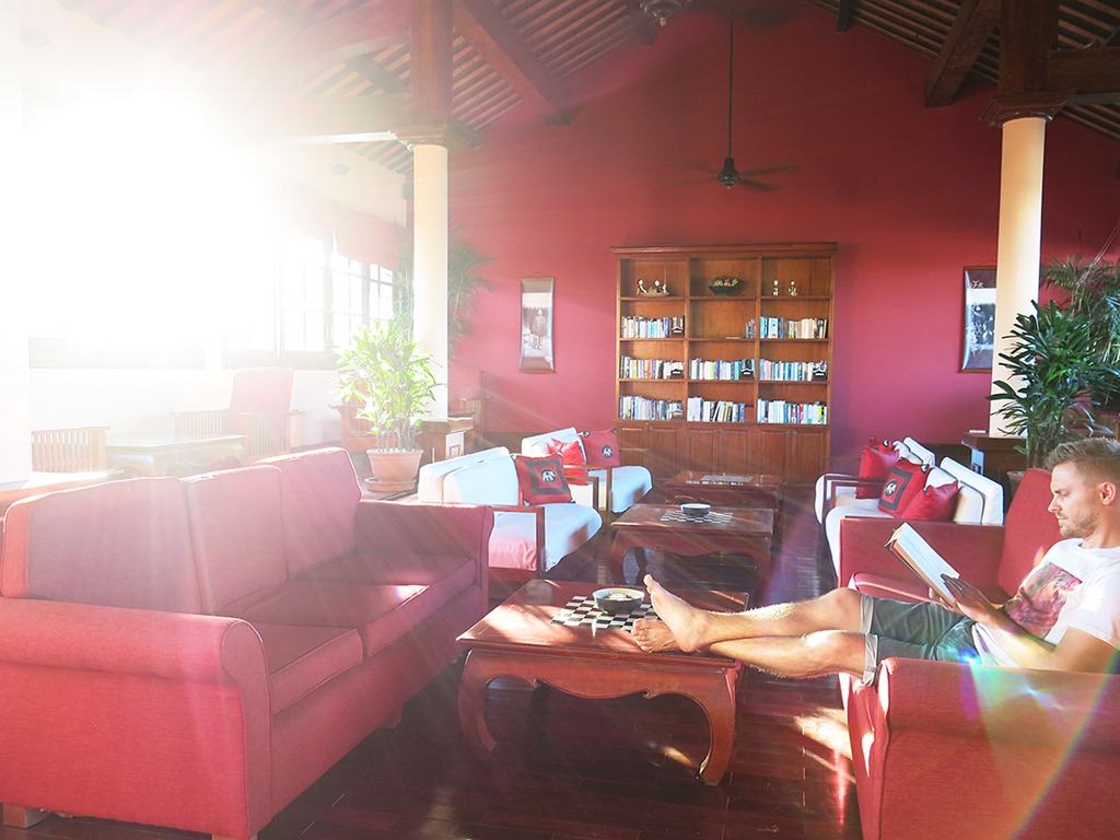 Victoria Hoi An, Vietnam, man sitting in the library and reading a book, red decor