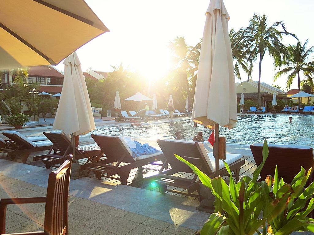 Victoria Hoi An, Vietnam, pool view at sunset, sun loungers and umbrellas