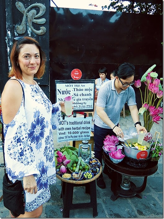 Hoi An Vietnam, woman smiling and holding a drink, man poring a drink, fruit and flowers