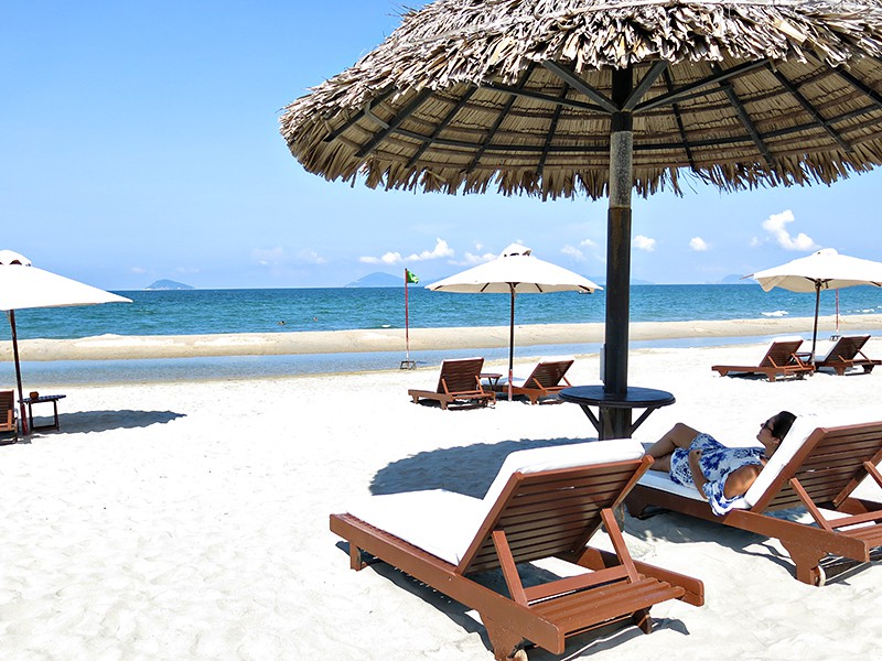 Lady at the beach laying on the sun loungers, beach umbrellas and beach view, Hoi An, Vietnam