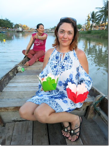 Hoi An Vietnam, woman sitting in a boat holding floating lanterns, one red  and one green, another woman rowing a boat 