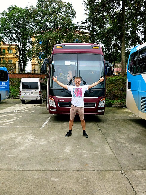 Getting from Hanoi to Sapa - Bus Hanoi to Sapa, man standing in front of the parked bus, arms up