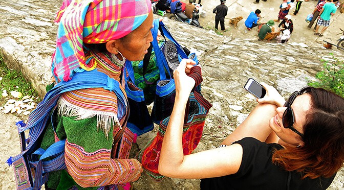 Bac Ha Markets in Vietnam, local woman dressed in traditional clothes showing a bag to a tourist