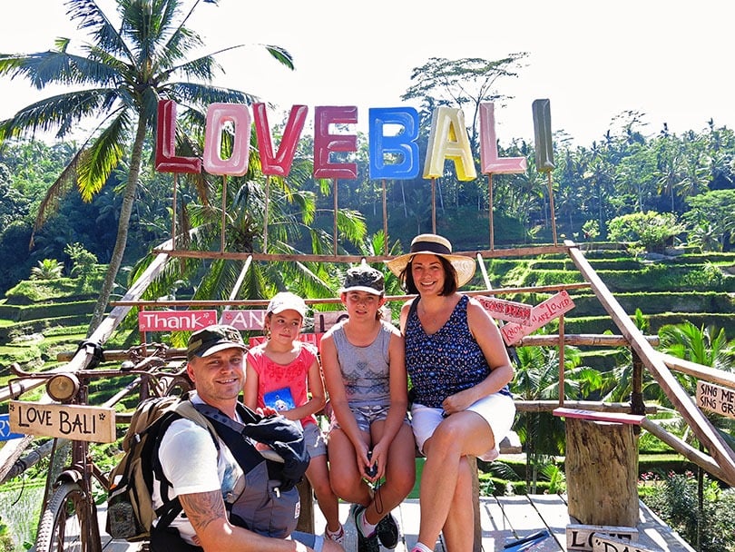 Family posing for a photo at the LOVE BALI sign in Bali in Indonesia, 