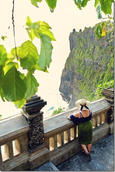 Uluwatu cliff temple, woman looking out from the view point onto the rocky shoreline