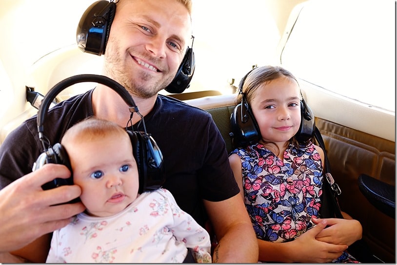 Father and two daughters on the small plane, headphones on, baby with big headphones