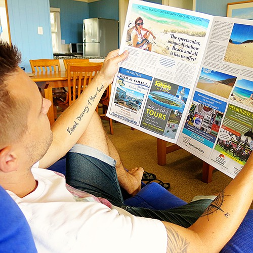 Rainbow Beach Cooloola Coast Community News, man holding a news paper, woman in the picture and some ads