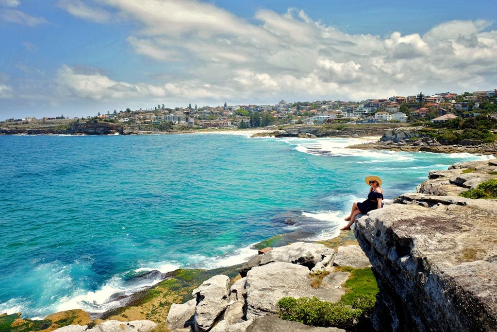 Sydney beaches, woman sitting on the rocky edge, view of the beaches, Australia