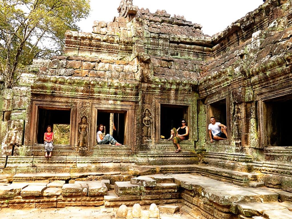 Cambodia, Angkor Wat Temples - Family posing in the windows of an old temple, 