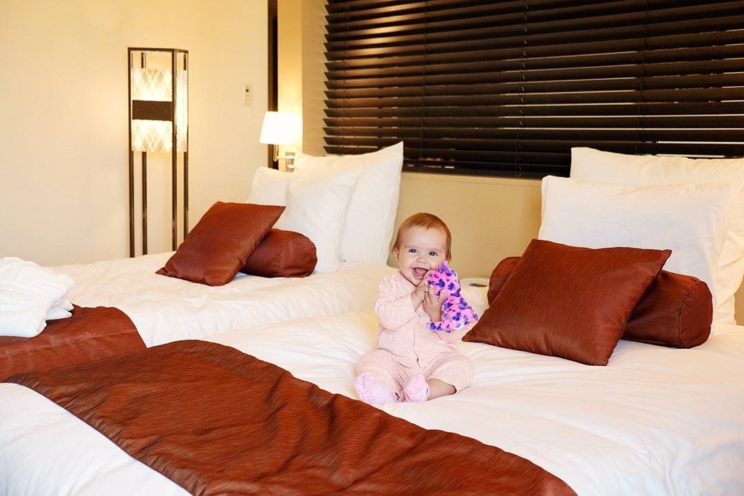 Ana Crown Plaza Kanazawa Accommodation, baby sitting on the bed in the bedroom