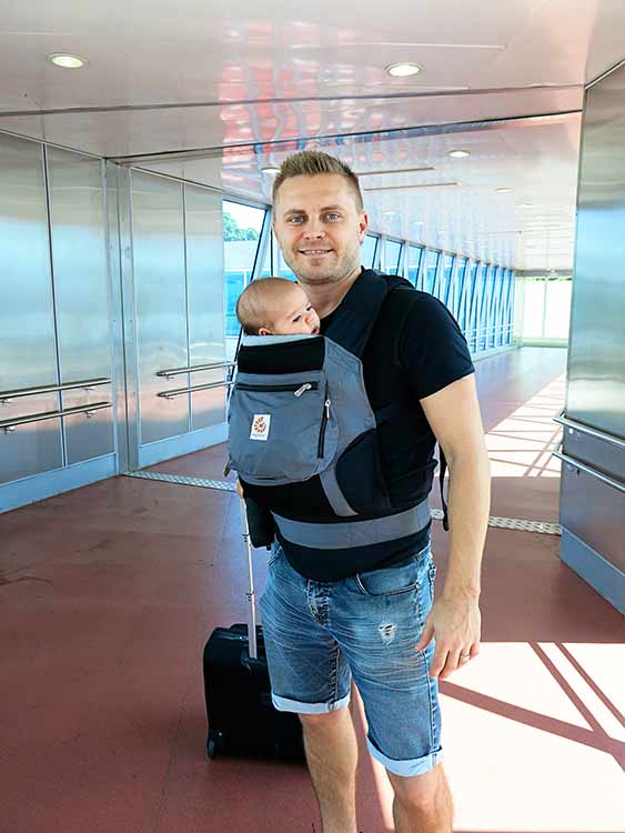 Man with a baby in the baby carrier at the airport hallway