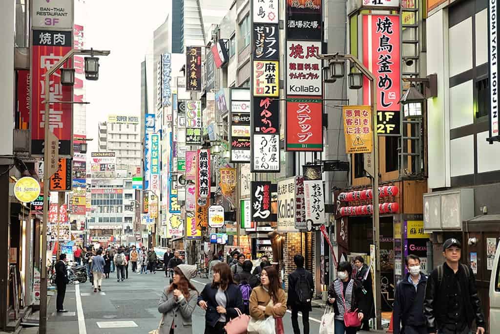  Kabikicho in Shinjuku Tokyo, a lot of people in the walking street, shops and colourful signs on the buildings