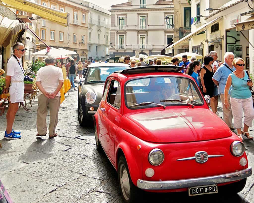 Small red Fiat car in the street of Amalfi Town, Amalfi Coast, Italy, tourists, buildings