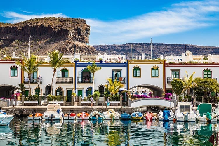 Port In Puerto de Mogan, Gran Canaria, Spain, colourful boats and buildings at the waters edge, mountains in the background