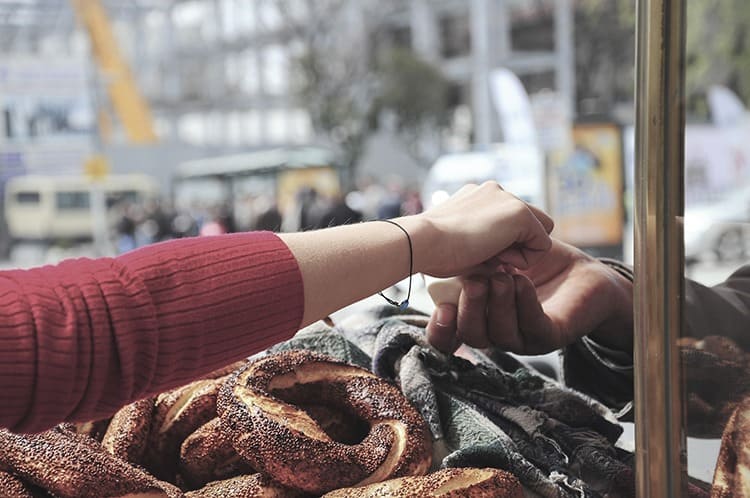 female hand giving money to get Turkish bagel at street