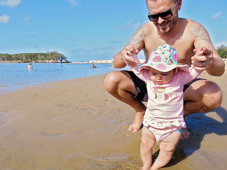 sunproof clothing with sun hat on baby with dad at the beach