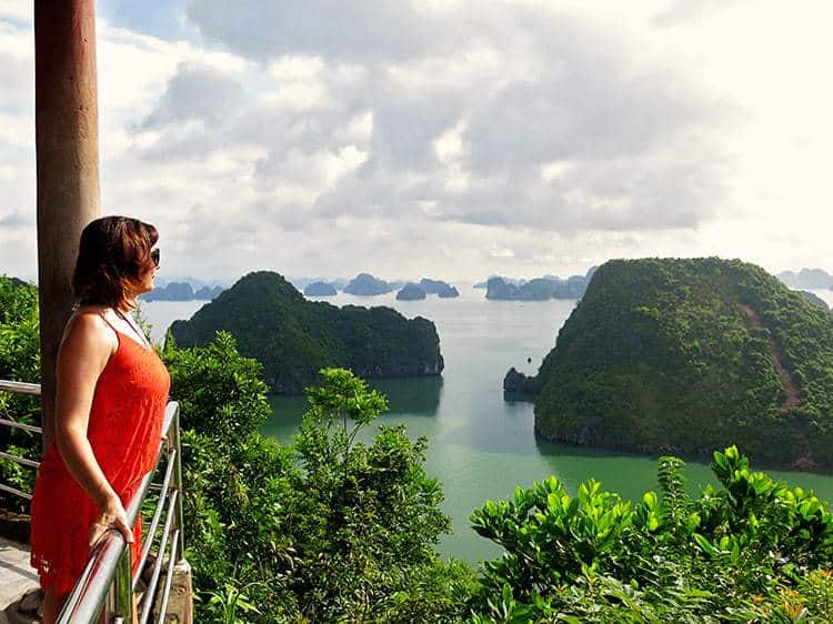 Woman  in red dress standing at the viewpoint looking out to the Halong Bay, rocky islands