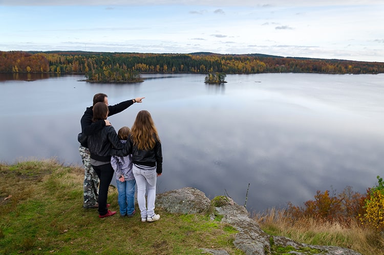 A family standing at the edge of the lake, man pointing away, 