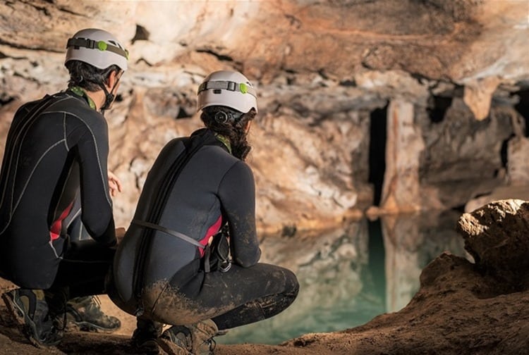 A couple of speleologists are exploring a cave, Punta degli Stretti Cave, Tuscany, Italy