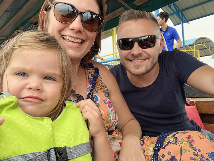 family on the boat smiling, daughter toddler sitting in a life jacket, sunglasses