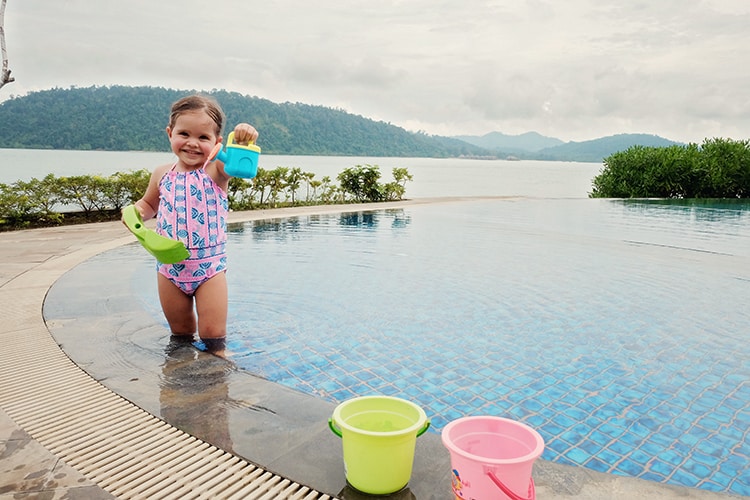 Telunas Private Island, Indonesia, a toddler playing with beach toys in the pool, view of the water and other island in the background