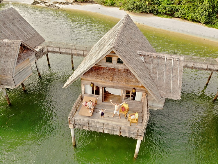 Telunas Private Island Resort, view from above of the over water villa, family standing on the verandah arms up