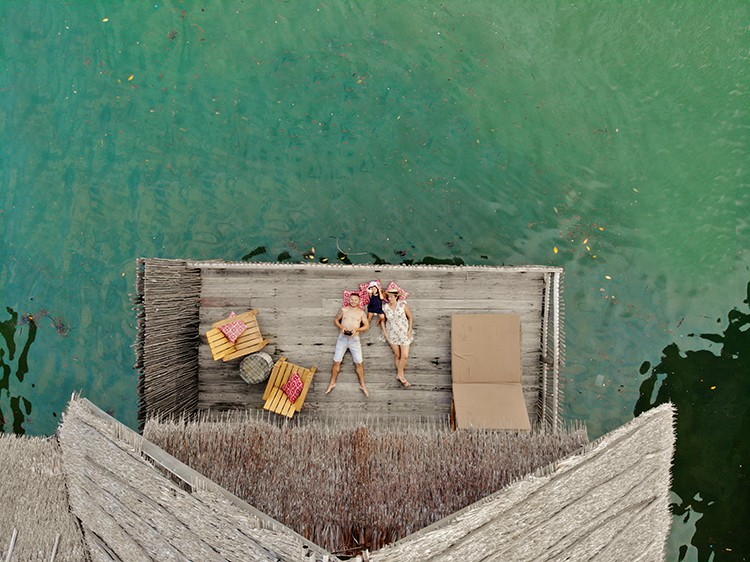 Telunas Private Island, Indonesia, family laying on the balcony of the over water villa, view from above, drone