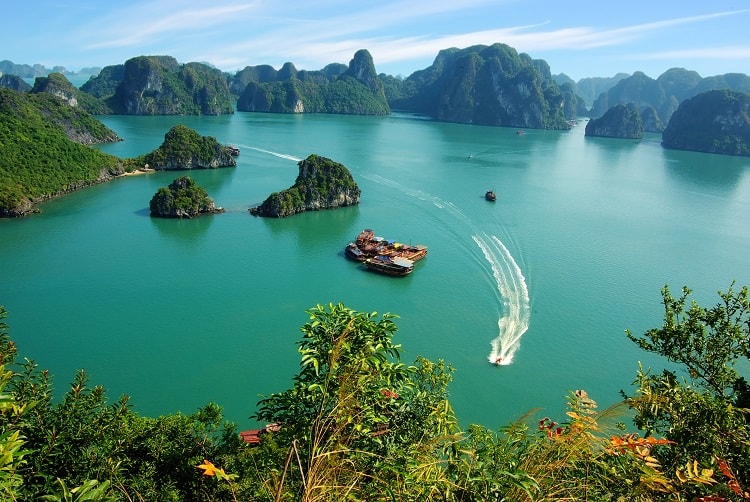 Photo from above of the speed boat and fishing village in Halong Bay, Vietnam, rocky islands all around