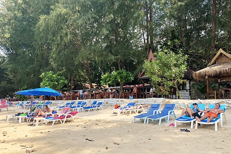 Ao Thong beach Khao Lak, Thailand, people laying down on sun loungers, some beach umbrellas