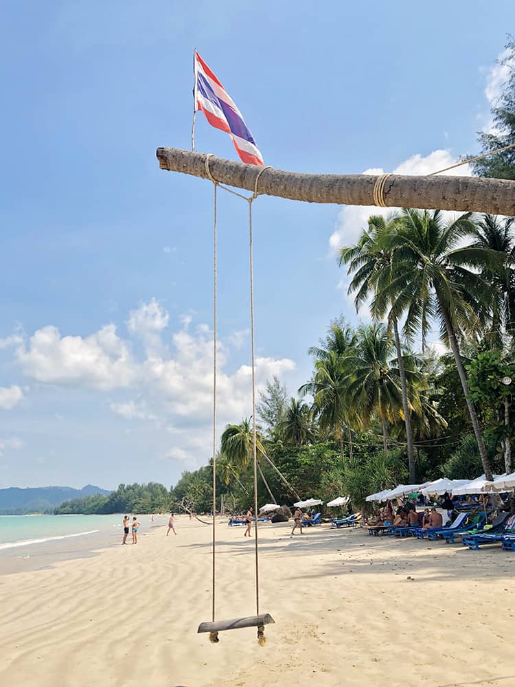 Best Beach in Khao Lak Thailand - Coconut Beach, beach rope swing tight to a palm tree, sun loungers and beach umbrellas, tourists, Thai flag