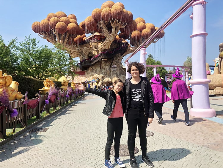 Gardaland Themepark, Italy, two teenagers girls posing on the footpath in front of a orange bubble tree house