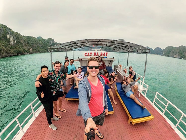 Halong Hideaway Cruise, Cat Ba Bay boat, man taking selfie on the top deck with a lot of tourists, 