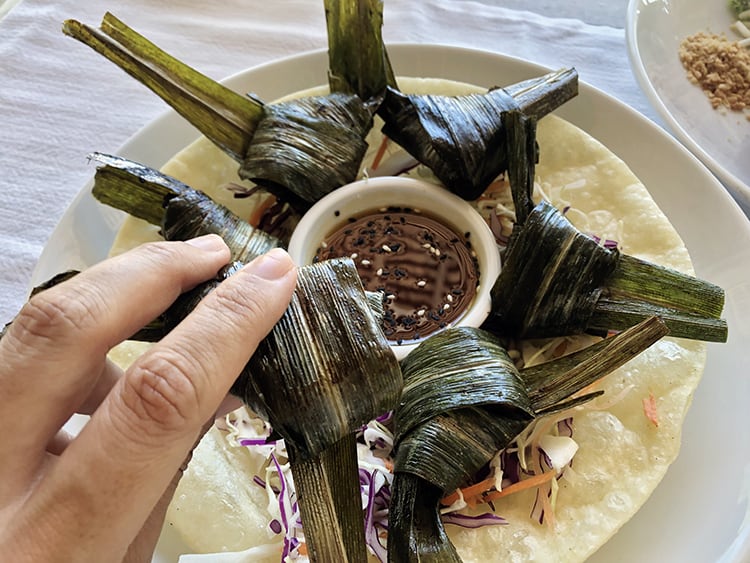 Koh Yao Noi Restaurant, hand holding a banana leaf wrapped Thai food