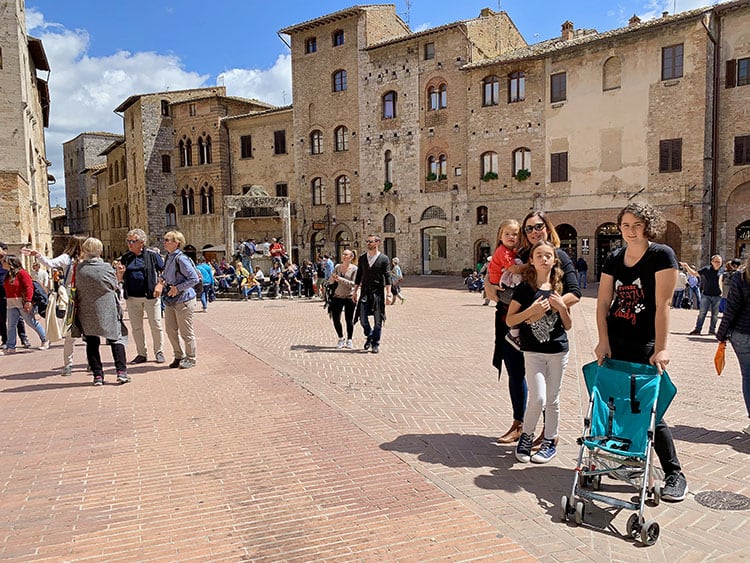 Piazza Della Cisterna San Gimignano, Italy, family posing in the square, tourists walking and standing