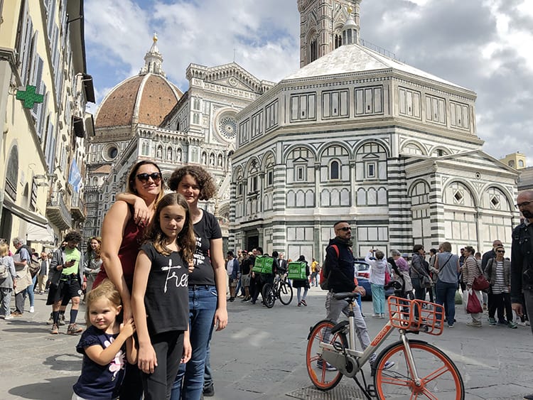 best cities in tuscany - Florence Italy, famous cathedral, mother and three daughters posing, smiling, man with bicycle, tourists