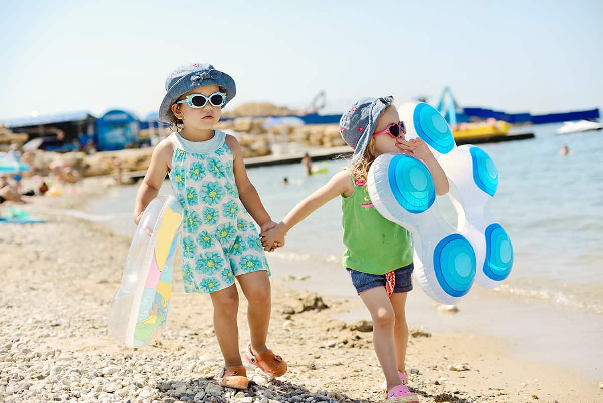 Best Water Shoes for Kids, kids with beach toys, sunglasses, hats at the beach