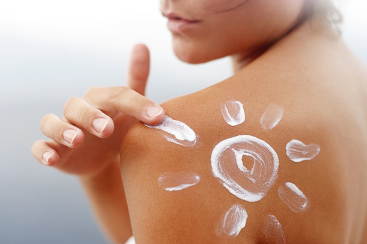 lady applying sunscreen onto her back with a sun shape
