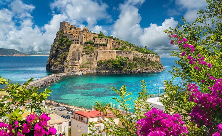 Landscape with Aragonese Castle,  Ischia island, Italy, with of the hill and old buildings, turquoise water, buildings, pink flowers