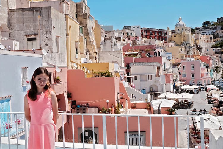 View from our Airbnb Patio in Procida, accommodation in Marina Corricelli, colourful buildings, young girl in pink dress posing