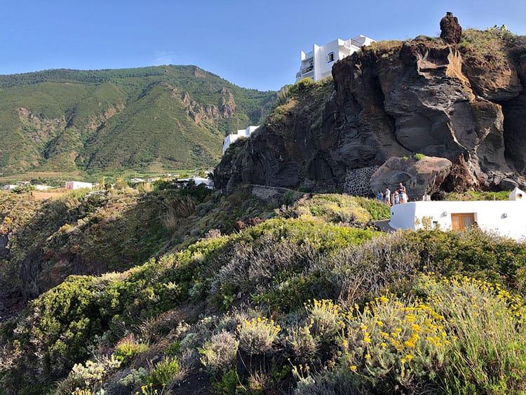 Salina-Aeolian-Islands, Italy, green and rocky view, yellow flowers, white buildings and some tourists