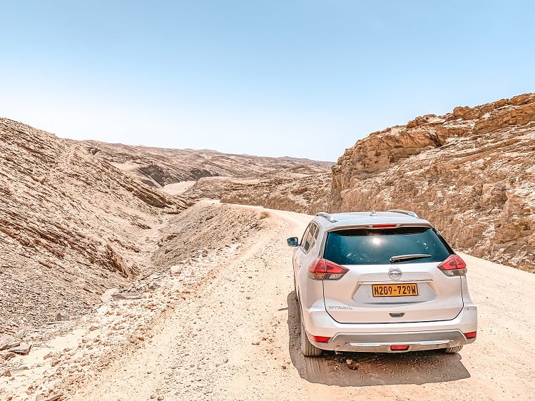 car on a dirt road in the rocky valley in the desert of Namibia