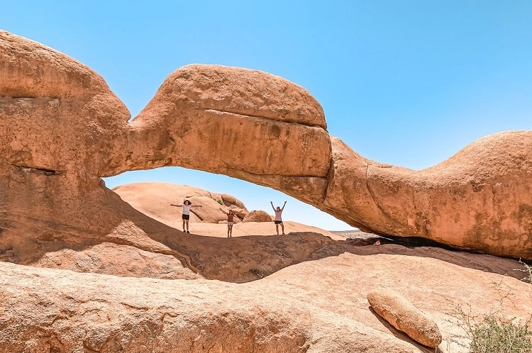 Travel Namibia with Kids Guide, Spitzkoppe Rock Arch, mother and daughters posing for a photo in the arch